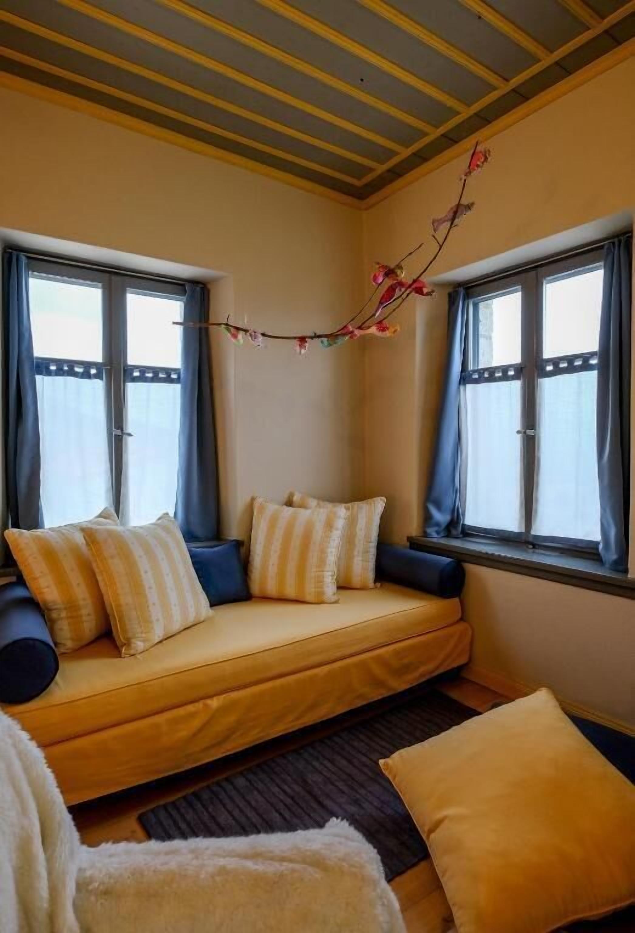 A cozy corner with a sofa, pillows, and a decorative branch.