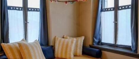 Un angolo accogliente con una poltrona, cuscini e un ramo decorativo.