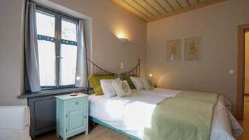 Cozy retreat with a bed, window, and nightstand, featuring framed artworks and a light fixture.