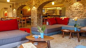 A cozy interior with stone walls, a dining area, and a seating area with sofas and tables. - KIRIAKI GUESTHOUSE & SUITES (Amfikleia-Elateia)