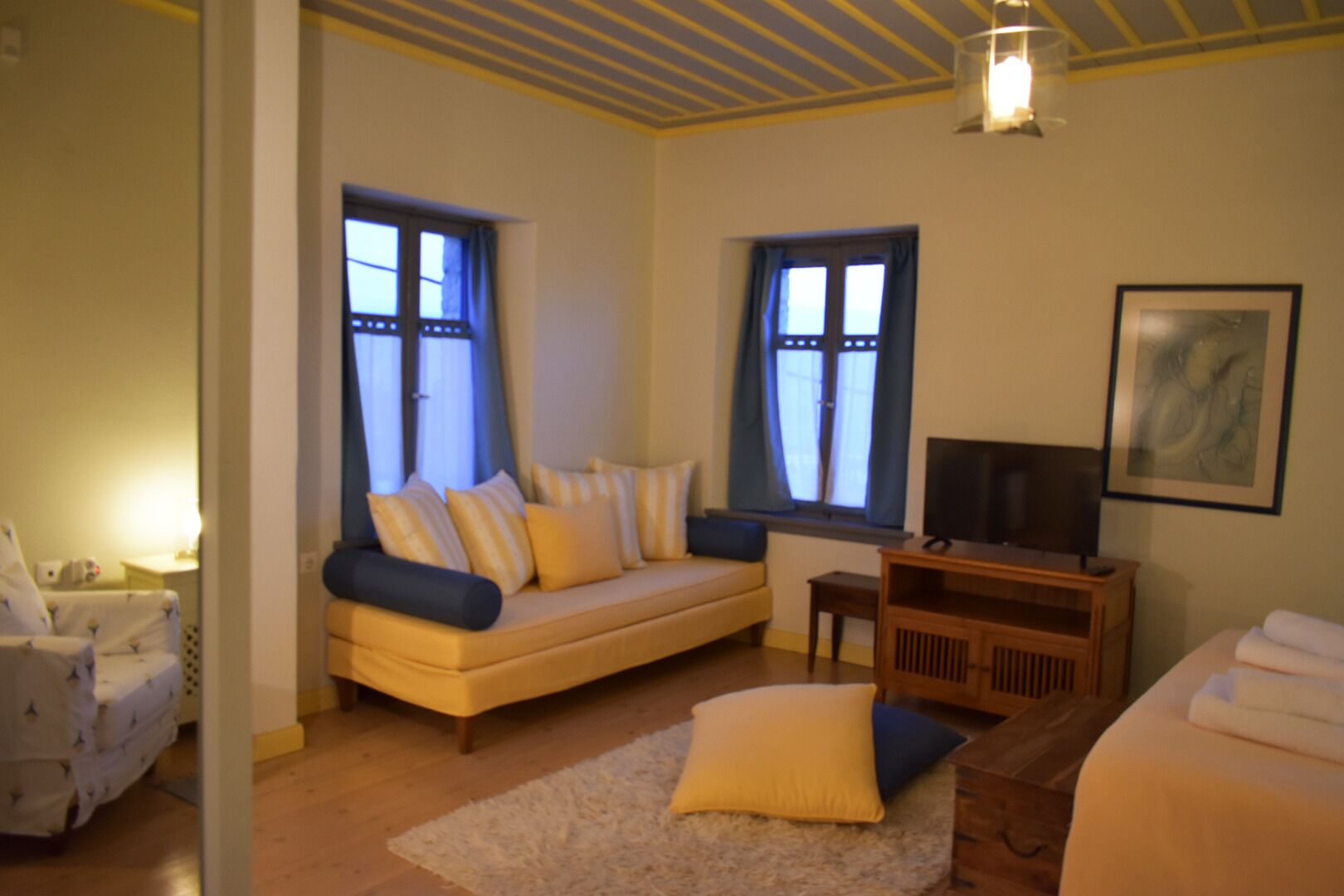 A cozy room with a sofa, a TV, and a bed.