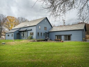 Ein zweistöckiges blaues Haus mit einer Veranda, einer Garage und einem großen Vorgarten.