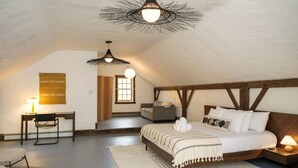 Et soveværelse med en seng, et skrivebord, en stol, en lampe og en pendel.