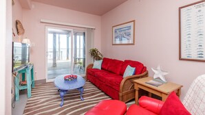 A cozy living room with a red sofa, a small round table, and a television on a teal stand. - Casa Copano by Miss Kitty’s (Rockport)