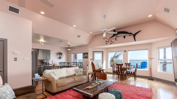 A spacious living area with a high ceiling, a dining table with chairs, a sofa, and a coffee table. - Casa Copano by Miss Kitty’s (Rockport)