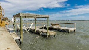 A wooden pier extending into calm water with a bench and hammock. - Casa Copano by Miss Kitty’s (Rockport)