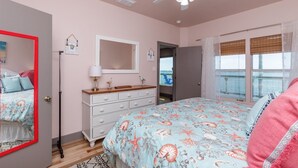 A bedroom with a bed, dresser, mirror, and a balcony with a view. - Casa Copano by Miss Kitty’s (Rockport)