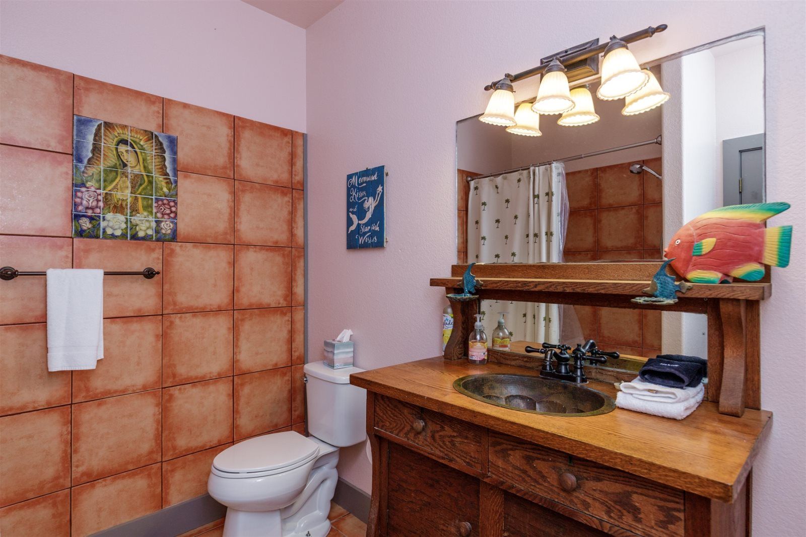 A bathroom with a wooden vanity, a sink, a mirror, and a toilet.