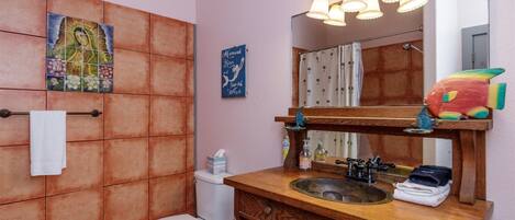 A bathroom with a wooden vanity, a sink, a mirror, and a toilet.