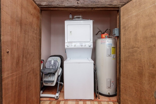 Ein kleiner Hauswirtschaftsraum mit Waschmaschine, Boiler und Kinderwagen.