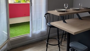 Et moderne køkken med et træbord, to stole og en skydedør, der fører ud til en balkon.