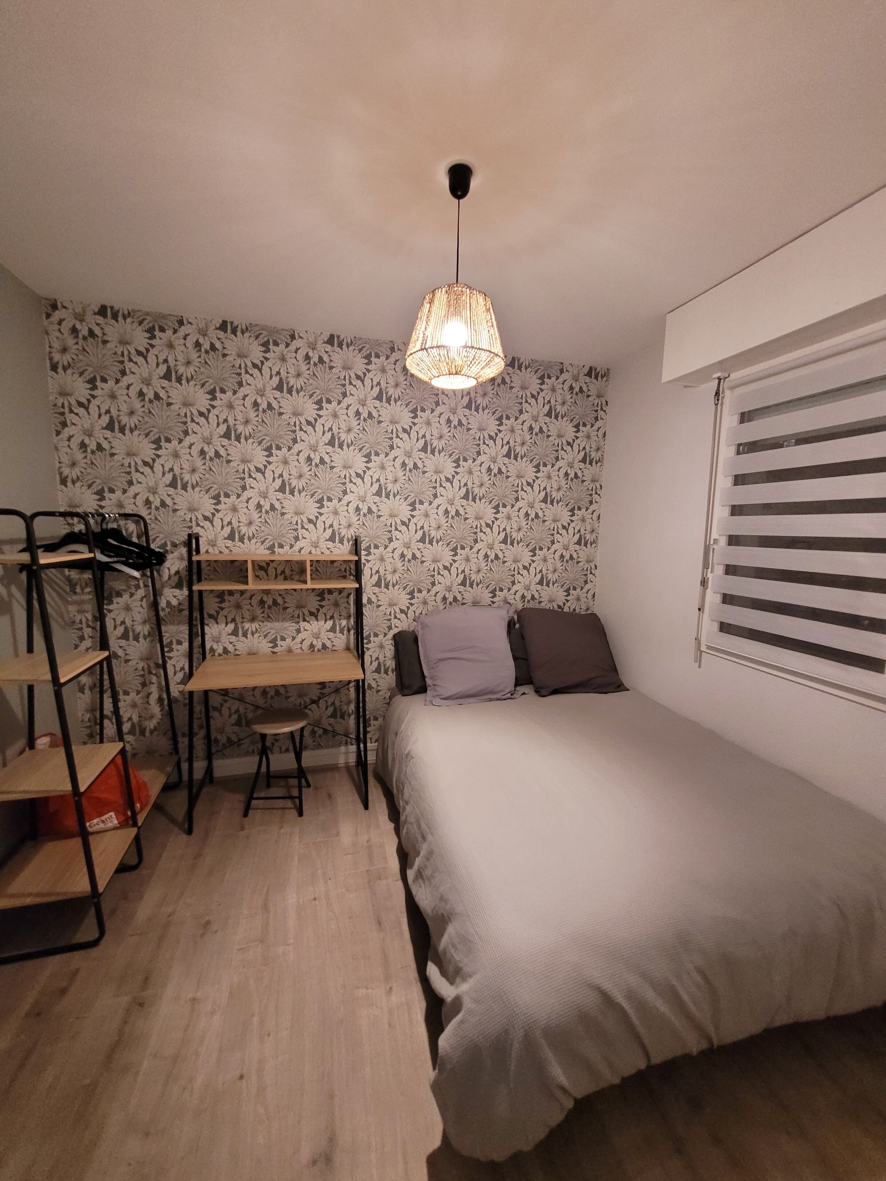 Un dormitorio con literas, un escritorio y una lámpara colgante.