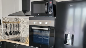 Et moderne køkken med en sort mikroovn, ovn og køleskab, et mønstret backsplash og en vanddispenser.