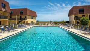 Une piscine rectangulaire à l’eau d’un bleu cristallin, entourée de chaises longues et d’une clôture.