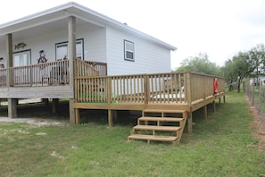 A house with a wooden deck, a small staircase, and a fenced yard. - Anchor House by Miss Kitty’s (Rockport)
