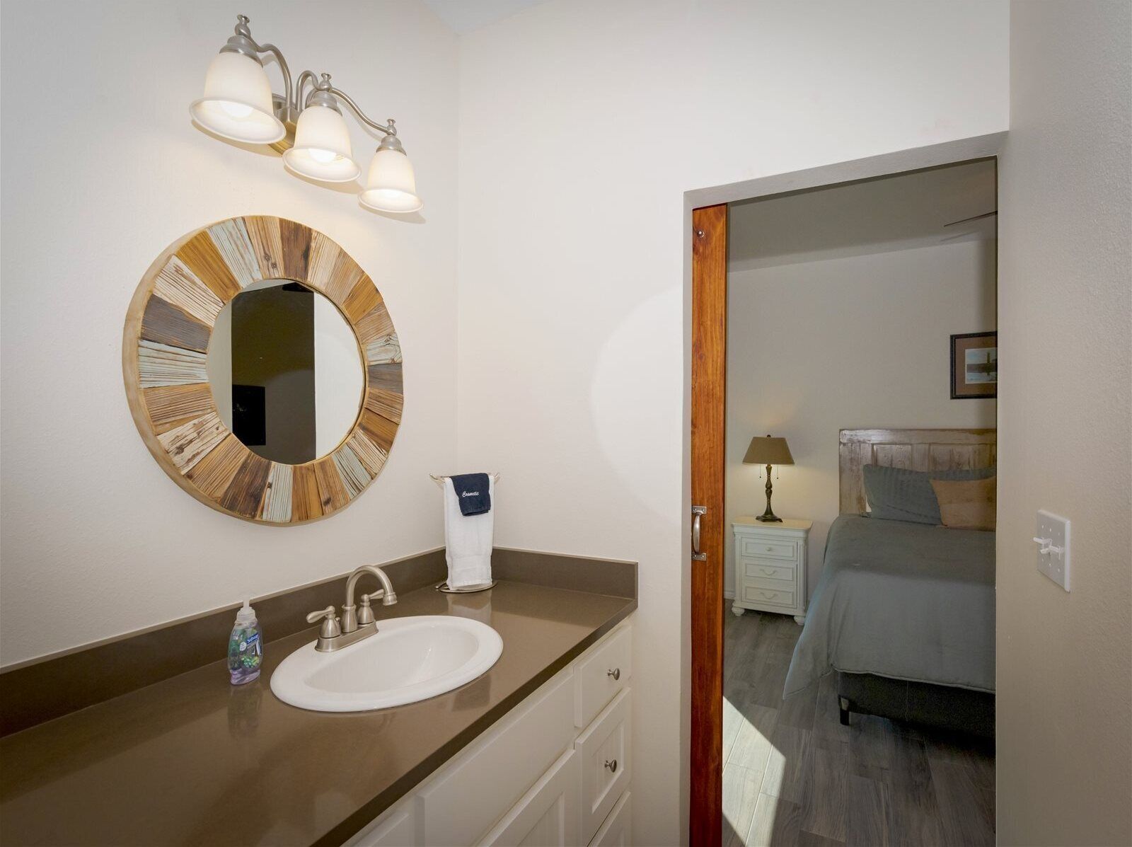 A bathroom with a round mirror, a sink, and a towel rack.