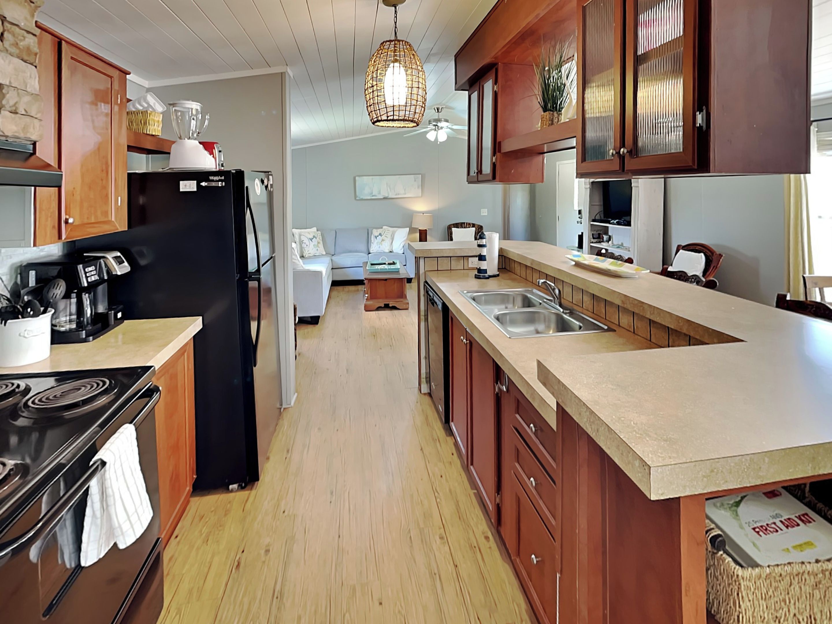 A modern kitchen with wooden cabinets, a black refrigerator, a stove, and a sink.