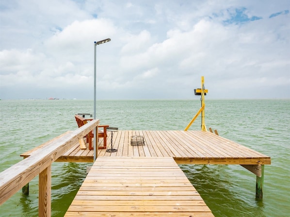 Un muelle de madera que se adentra en aguas tranquilas, con un banco y un farol.