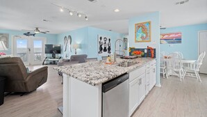 A spacious living area with a large island, a dining table with white chairs, and a kitchen with white cabinets.
