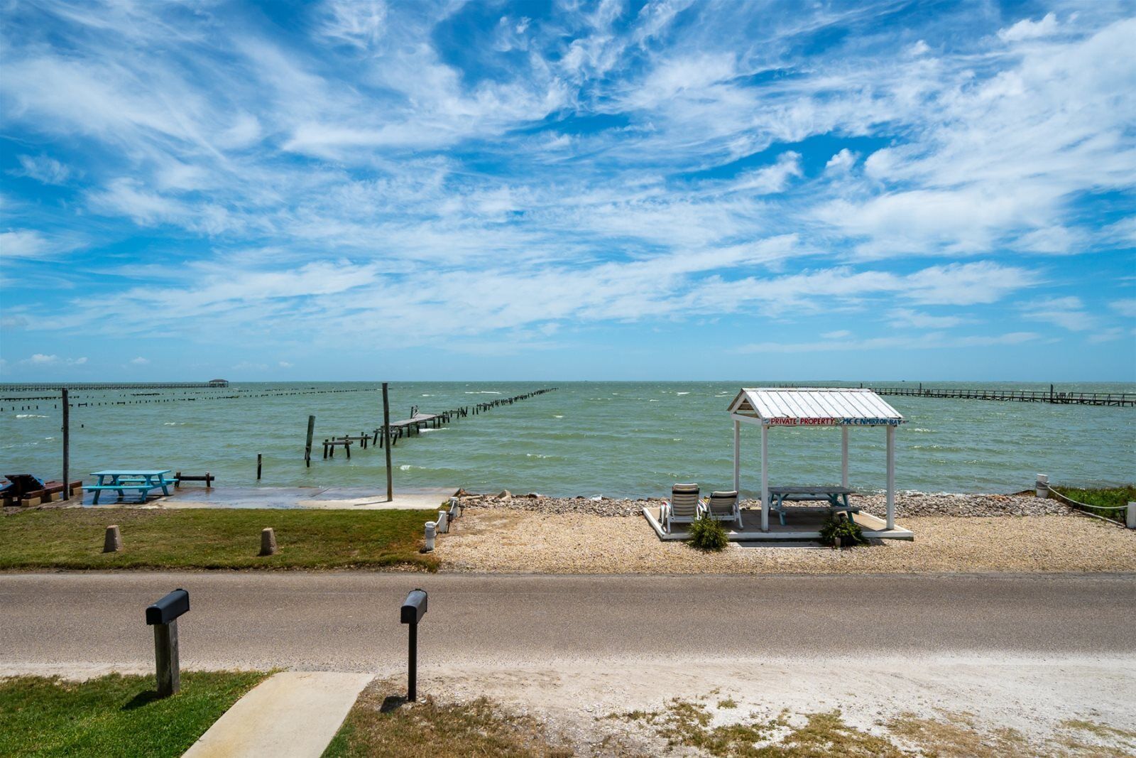 Ein Strand mit einer Holzsteg, der sich ins Wasser erstreckt, einem Gazebo und einem Picknicktisch.