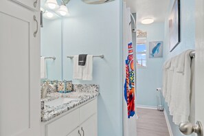 Un baño con encimera de mármol, un perchero y una cortina de ducha.