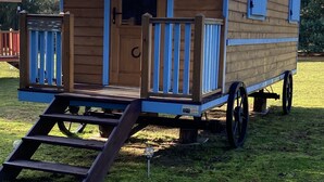 A wooden RV with a front porch, a door, and a ramp leading to the entrance. - Roulotte "cecile" Pour un Séjour Atypique en Roulotte (Digoin)