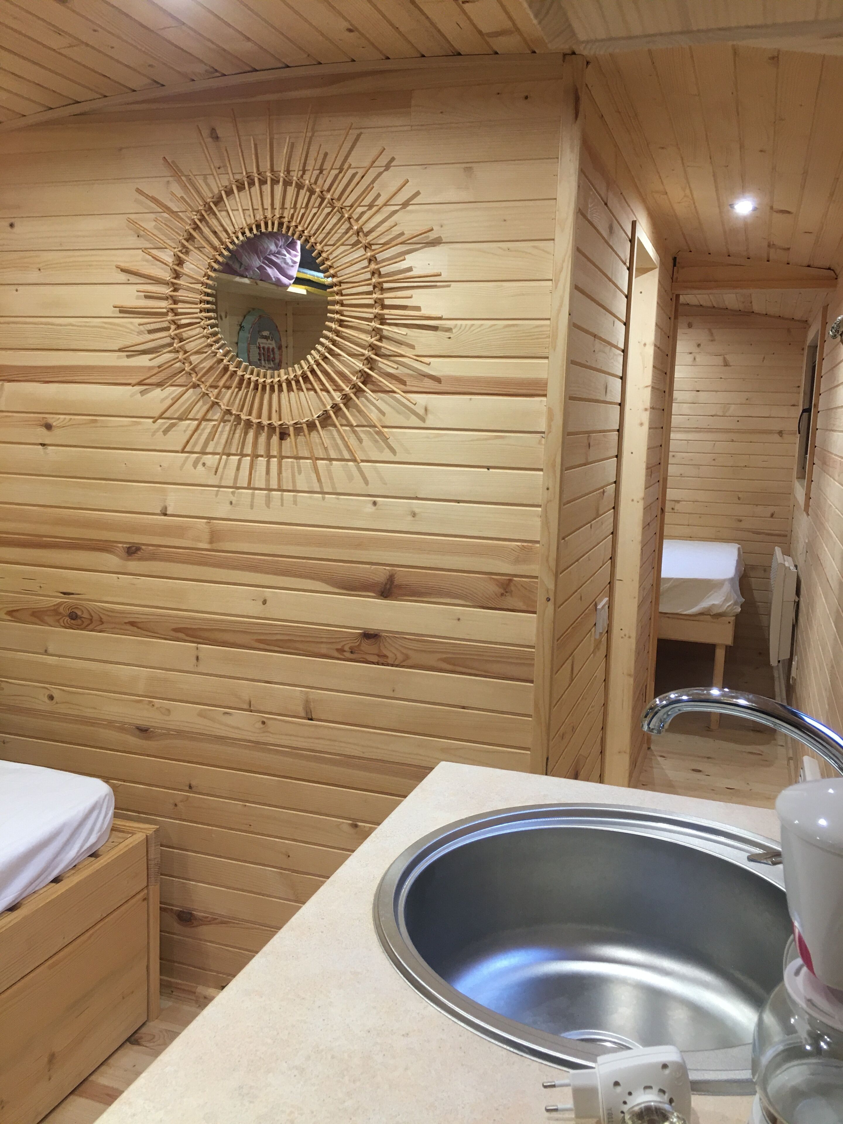 L’intérieur d’une cabane en bois, avec une décoration murale circulaire, un évier et un petit banc en bois.