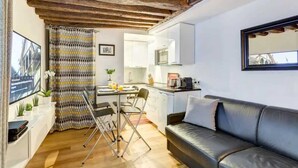 A compact living space with a dining area, kitchenette, and a sofa. - Chic Marais Retreat | Steps to Cafes & Notre Dame (Paris)