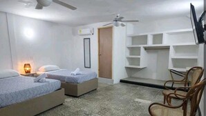 A hotel room with two beds, a chair, a TV, and built-in shelves. - M4-J HABITACION EN EL CENTRO HISTORICO (Cartagena)