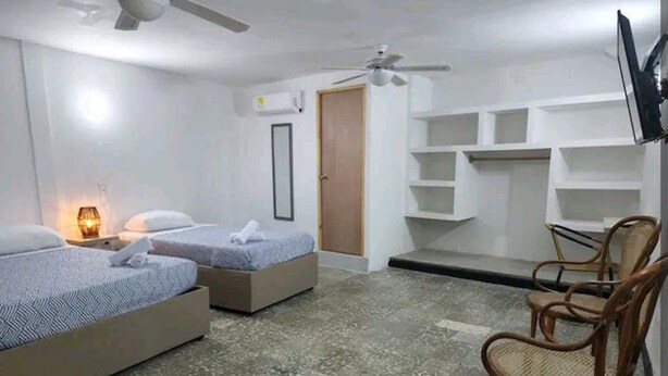 Ein Hotelzimmer mit zwei Betten, einem Sessel, einem Fernseher und eingebauten Regalen.