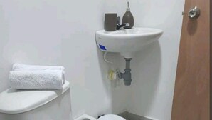 Ein kleines Badezimmer mit Toilette, Waschbecken und einem Handtuch an der Wand.