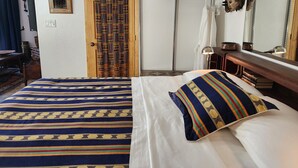 A room with a bed, a wooden door, a mirror, and a shelf with decorative items. - Come experience a taste of Africa nestled in the foothills of Santa Fe.  (Santa Fe)