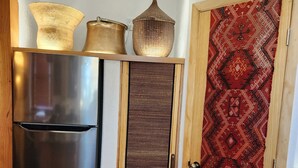 A compact kitchen with a stainless steel refrigerator, a wooden door with a patterned design, and a textured wall panel. - Come experience a taste of Africa nestled in the foothills of Santa Fe.  (Santa Fe)