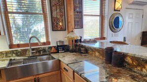 A kitchen with a granite countertop, wooden cabinets, a stainless steel sink, and a window with blinds. - Come experience a taste of Africa nestled in the foothills of Santa Fe.  (Santa Fe)