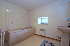 A modern bathroom with a bathtub, a sink, and a window.