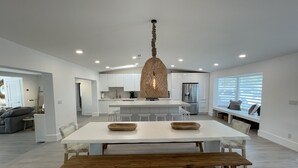 A modern kitchen with white cabinets, a central island, and a hanging light fixture. - Modern Beach LakeFront House in Miami ! (Miami)