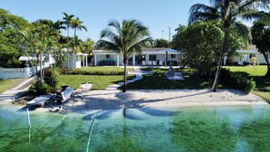 A beachfront property with clear water, palm trees, and a pool area. - Modern Beach LakeFront House in Miami ! (Miami)