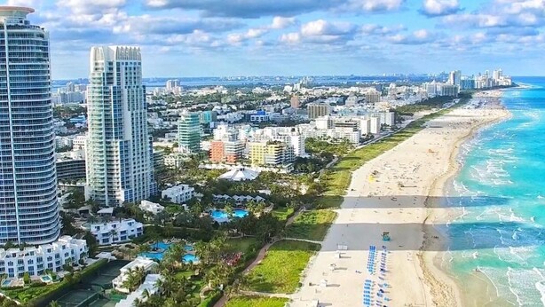 A coastal cityscape with high-rise buildings, a sandy beach, and a clear blue sky. - Modern Beach LakeFront House in Miami ! (Miami)