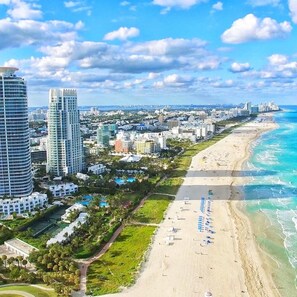 A coastal cityscape with high-rise buildings, a sandy beach, and a clear blue sky. - Modern Beach LakeFront House in Miami ! (Miami)