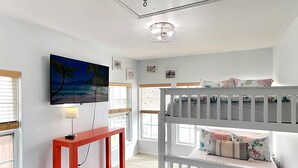 A room with a bunk bed, a TV mounted on the wall, a small red console table, and a window with blinds. - Hook, Wine & Sinker by Miss Kitty’s (Rockport)