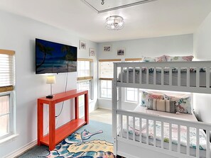 A room with a bunk bed, a TV mounted on the wall, a small red console table, and a window with blinds. - Hook, Wine & Sinker by Miss Kitty’s (Rockport)