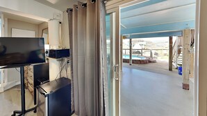 A room with a desk, computer, and a sliding glass door leading to an outdoor area with a pool. - Hook, Wine & Sinker by Miss Kitty’s (Rockport)
