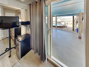 A room with a desk, computer, and a sliding glass door leading to an outdoor area with a pool.