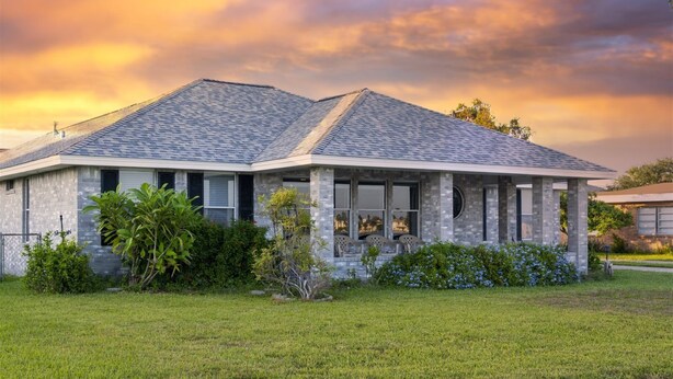 A two-story house with a stone facade, a covered porch, and a well-maintained lawn. - Attitude Adjustment by Miss Kitty’s (Rockport)