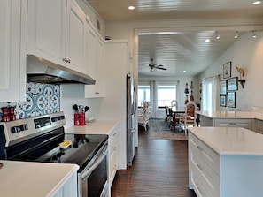 A modern kitchen with white cabinetry, a stainless steel range, and a red spice rack.