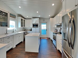 A modern kitchen with white cabinetry, stainless steel appliances, and a herringbone wood floor.