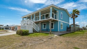 Uma casa de dois andares com varanda coberta e escadaria que leva ao segundo pavimento.