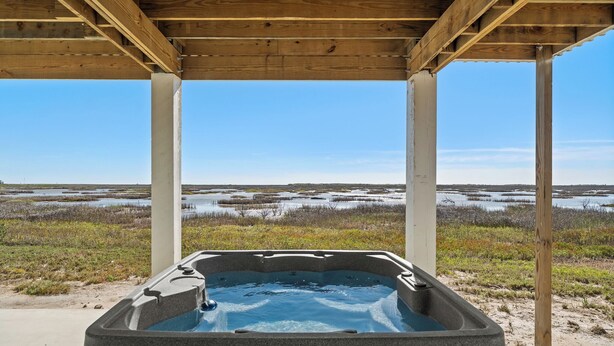 A hot tub under a wooden pergola with a view of a marshy landscape. - Birds on the Bay by Miss Kitty’s (Rockport)