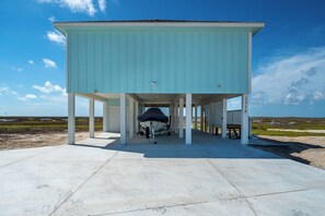 A light blue building with a covered area and a boat docked underneath.