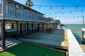 A waterfront property with a wooden deck, outdoor seating, and a view of the ocean. - Frisco Flats by Miss Kitty’s (Rockport)